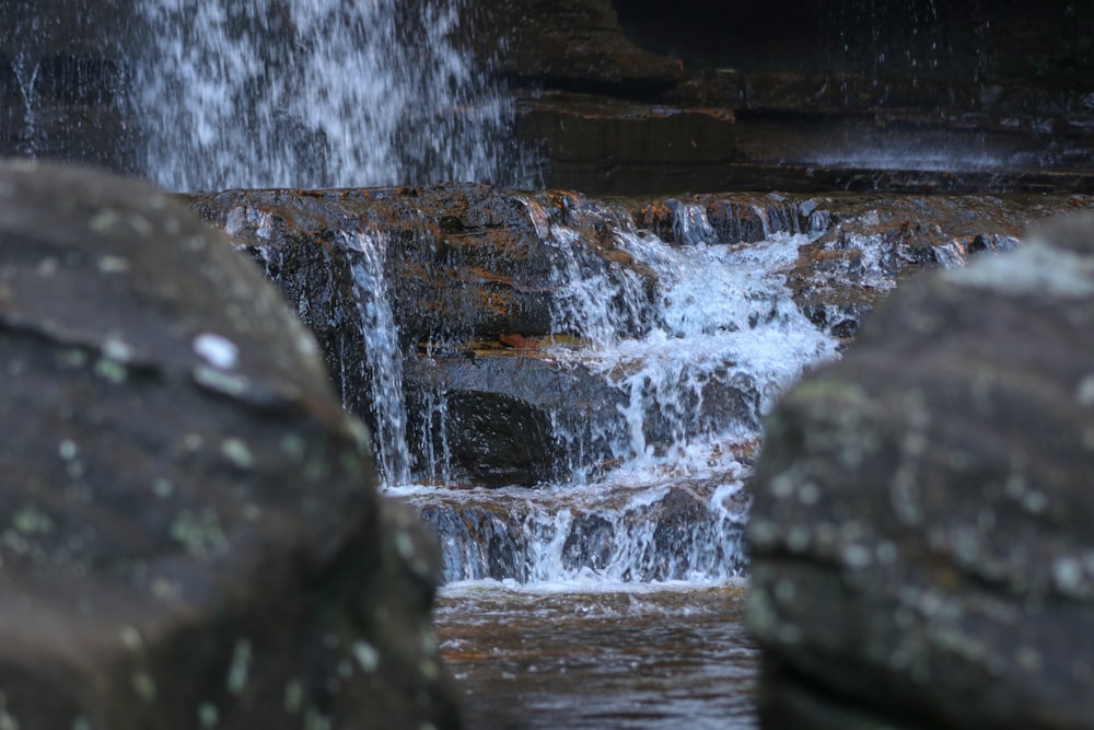 a close up of a waterfall with rocks in the foreground