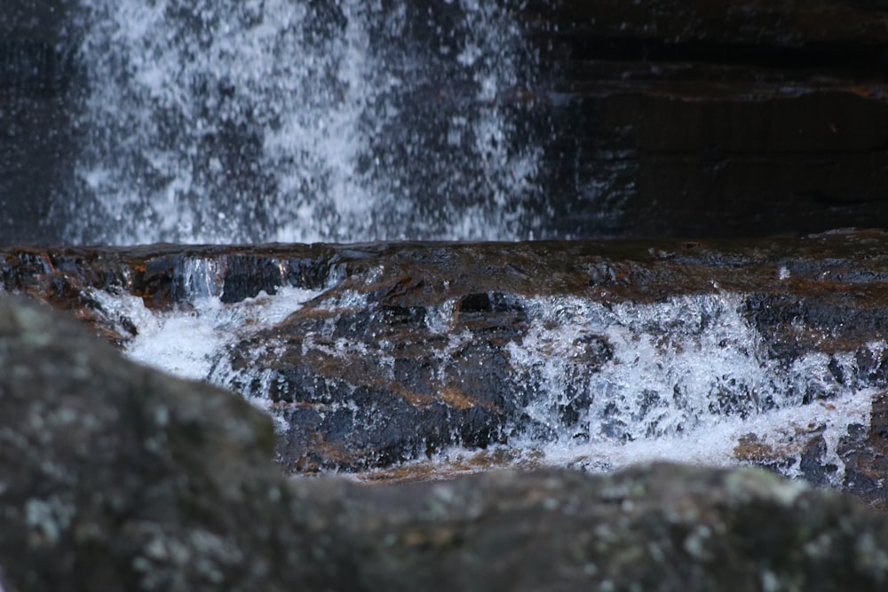 a close up of a waterfall with rocks in the foreground