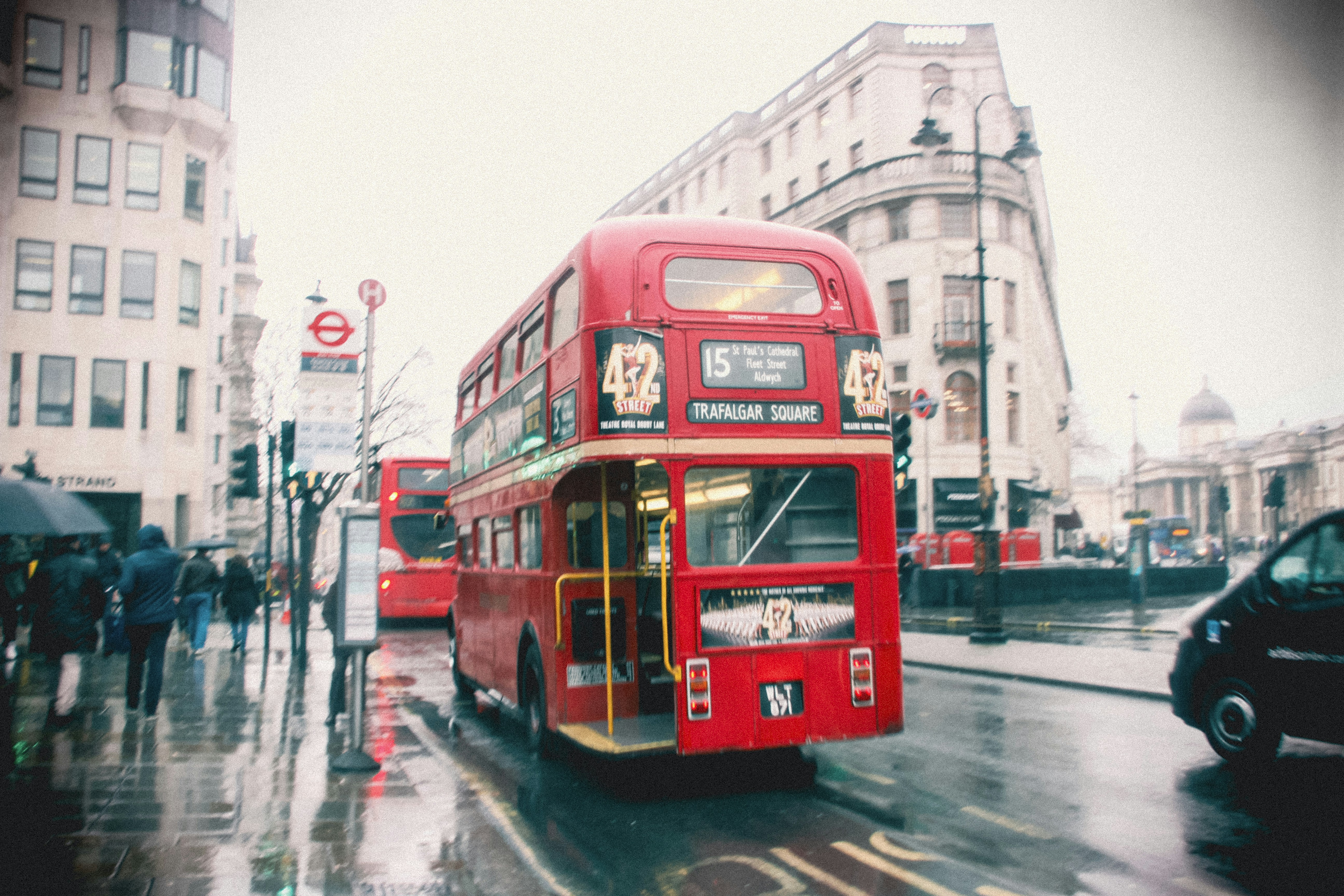 a red double decker bus driving down a street