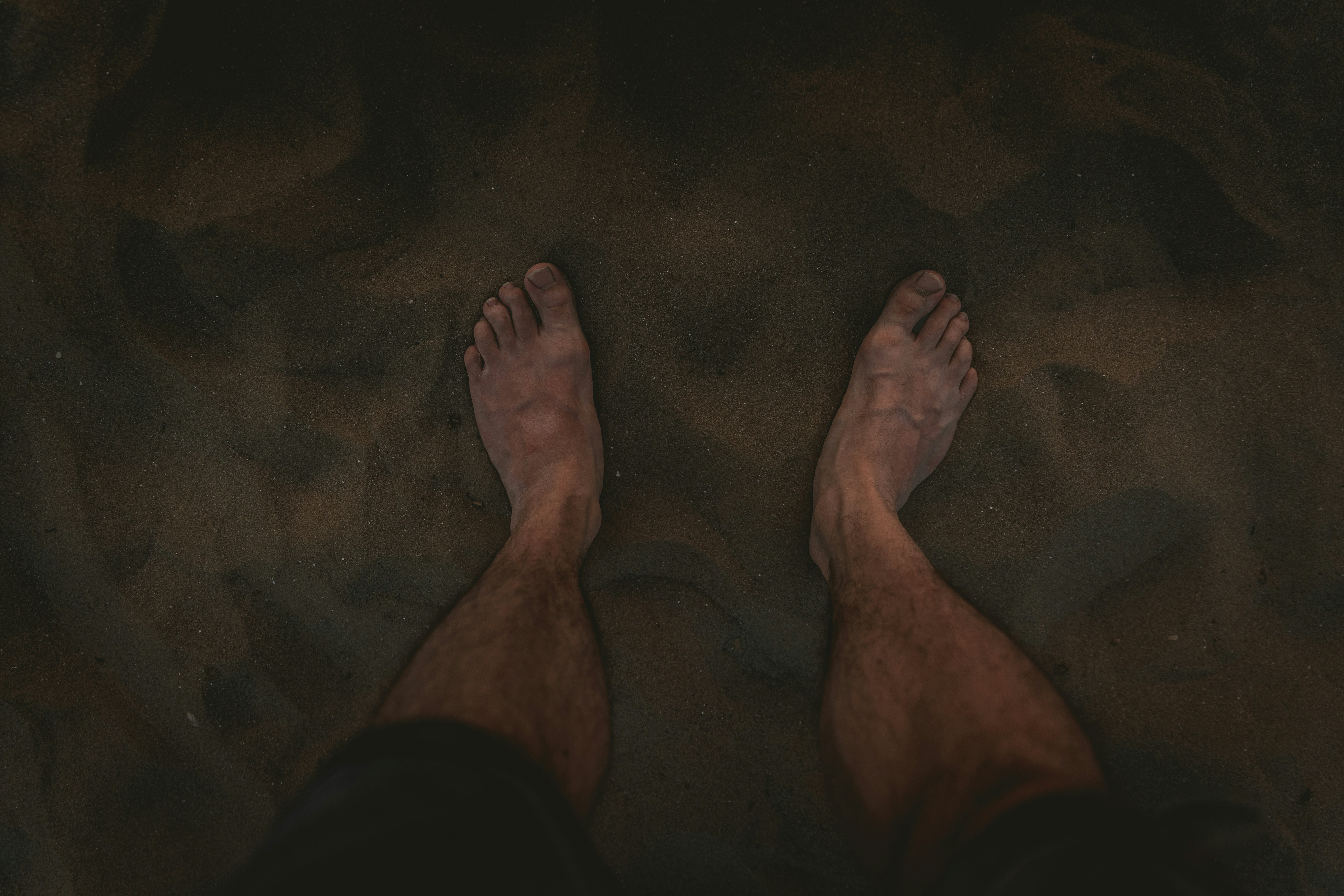 a person standing in the sand with their feet in the sand