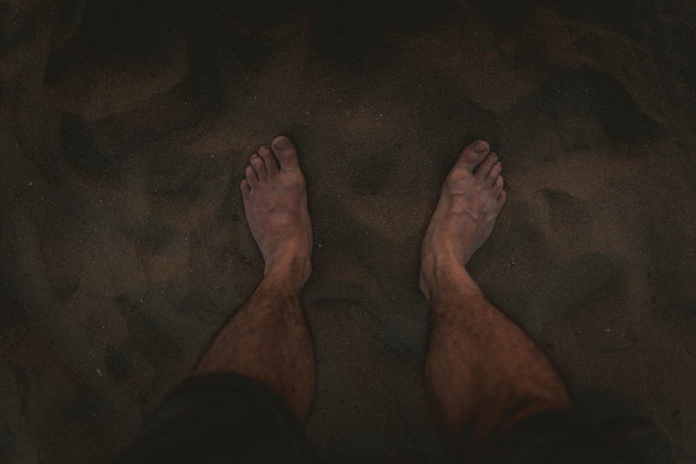 a person standing in the sand with their feet in the sand