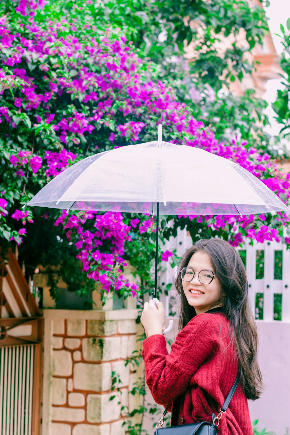 a woman in a red sweater holding an umbrella