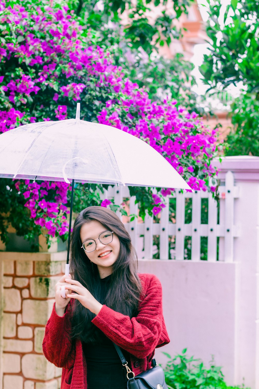 a woman in a red sweater holding an umbrella