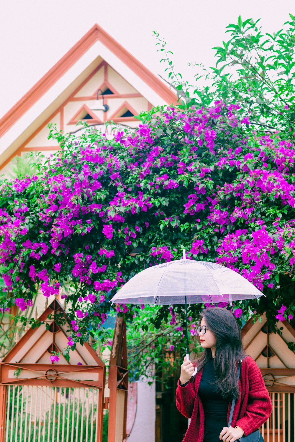 a woman standing under an umbrella in front of a house