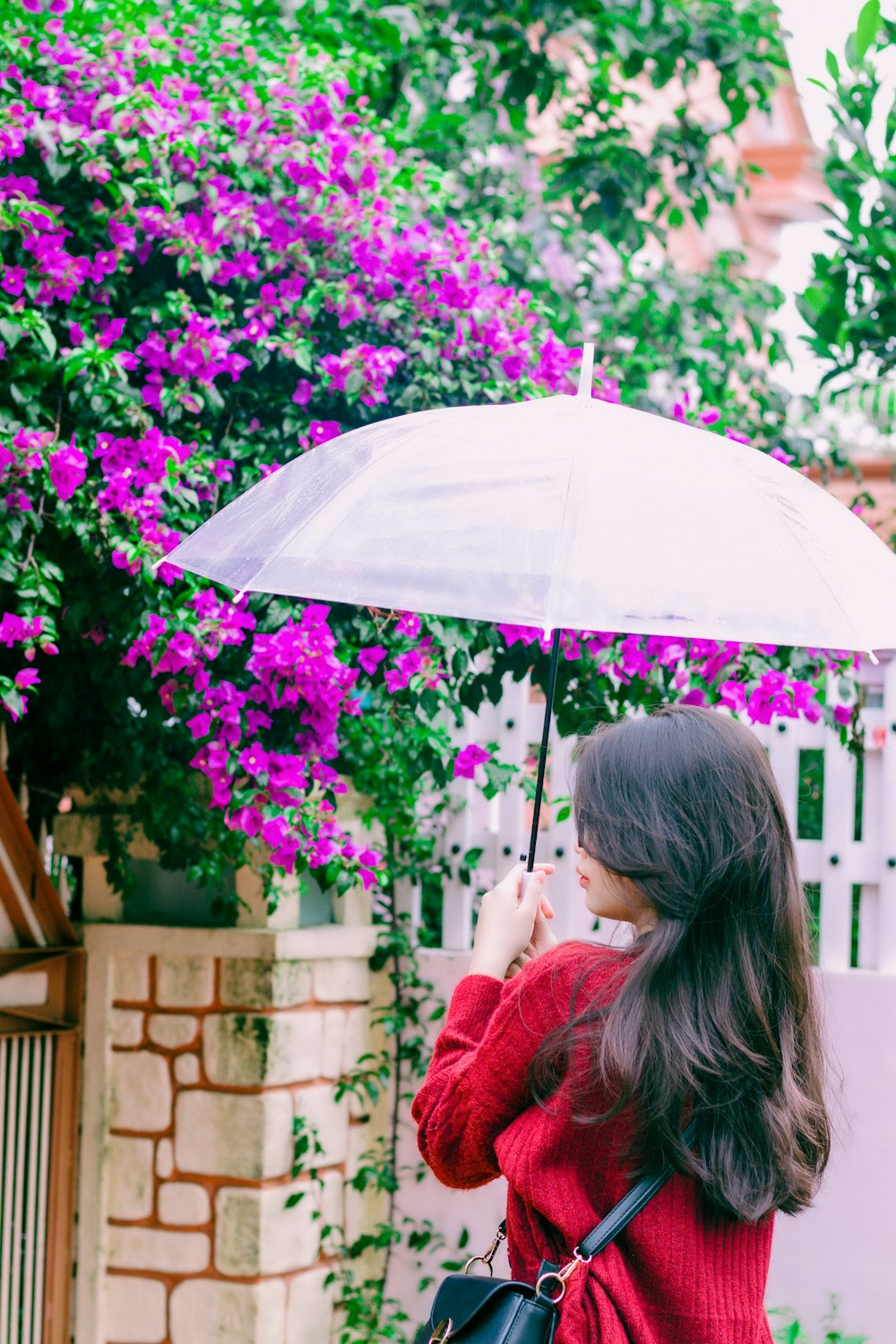 a woman in a red sweater holding an umbrella