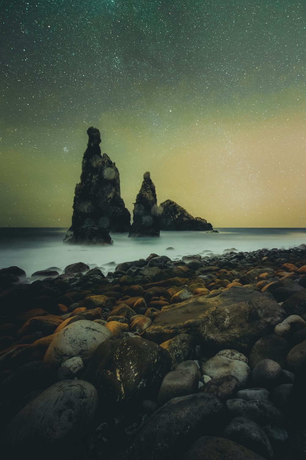 a rocky beach under a night sky filled with stars