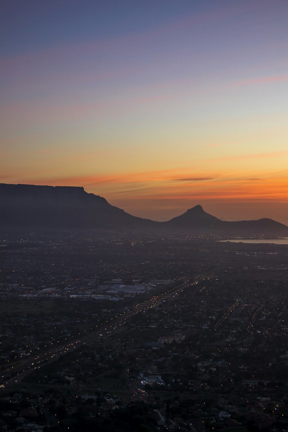 the sun is setting over a city with mountains in the background