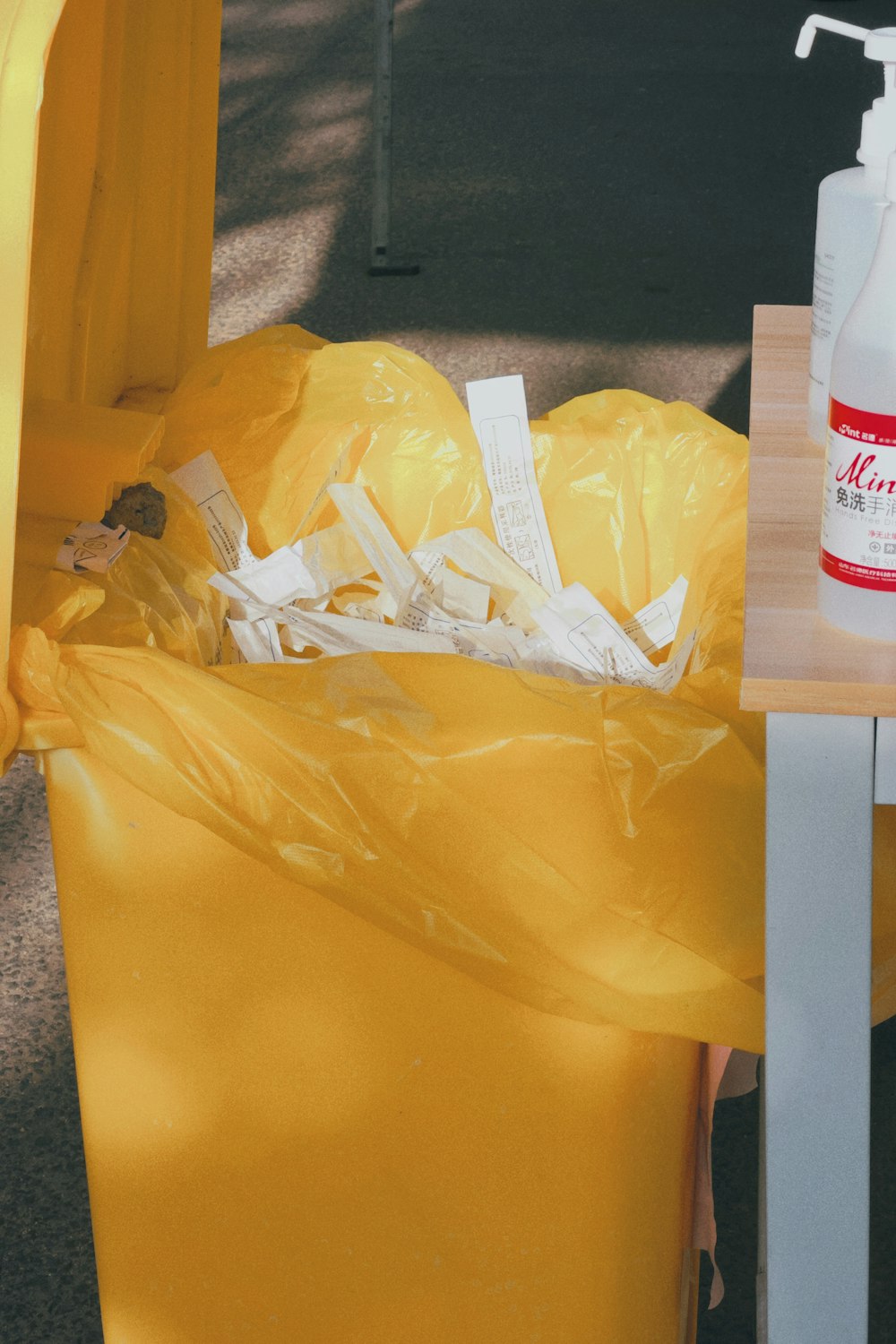 a yellow trash can with a bottle of cleaner next to it
