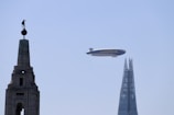 an airplane flying over a tall building with a statue on top of it