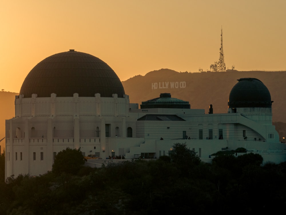 a large building with a sunset in the background with Griffith Observatory in the background