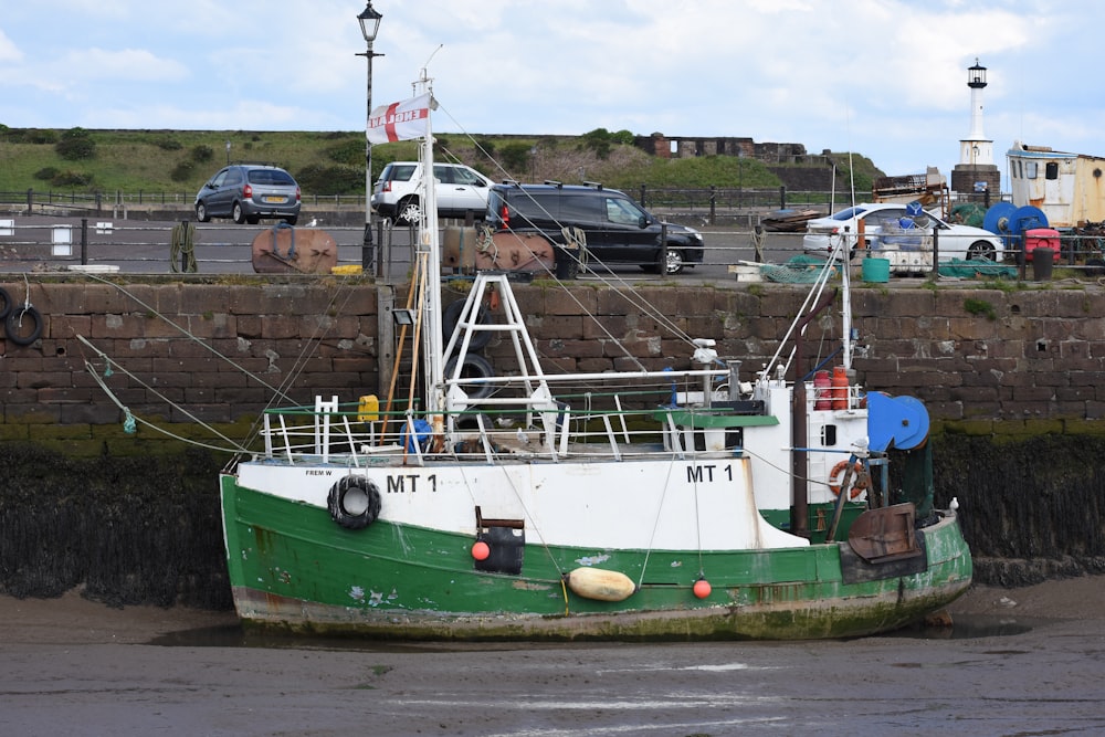 a green and white boat sitting on top of a body of water