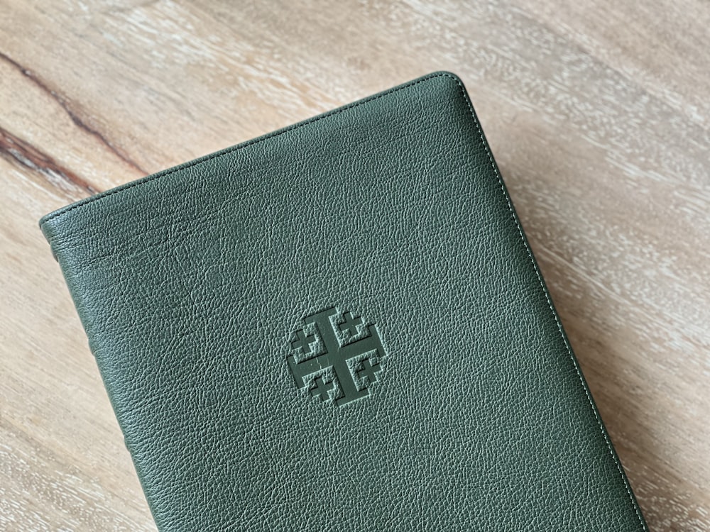 a green leather wallet sitting on top of a wooden table