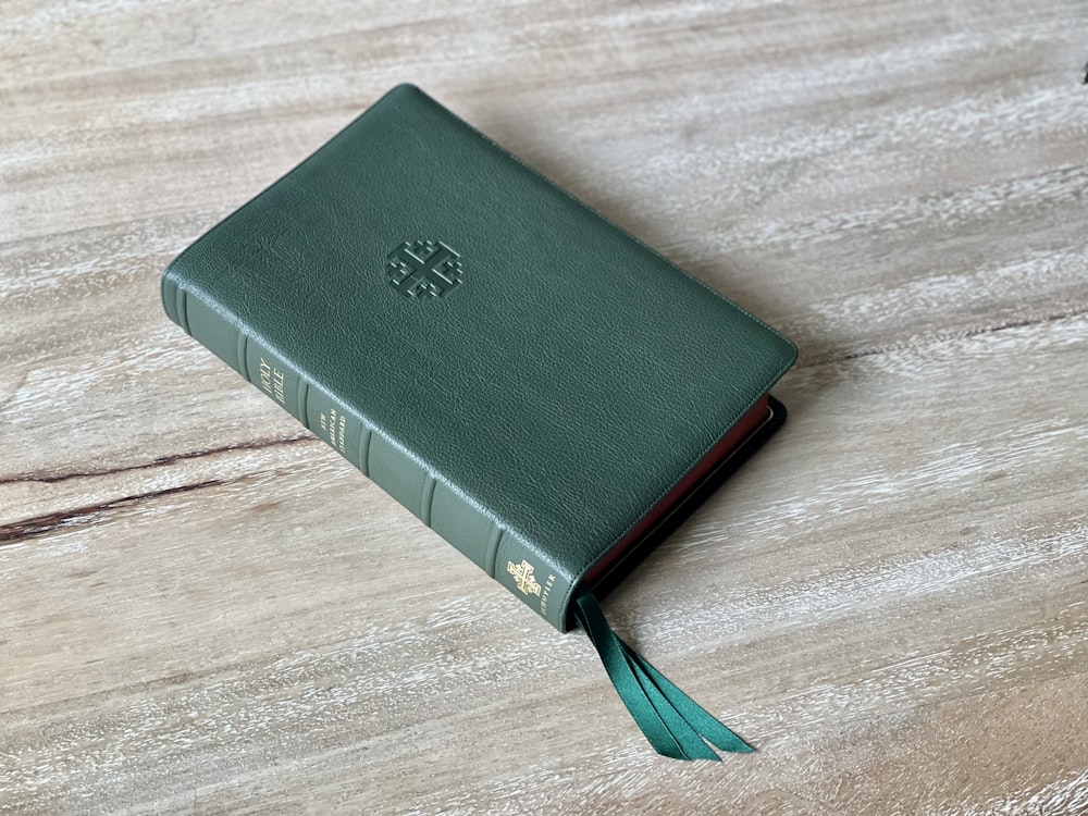un livre vert posé sur une table en bois