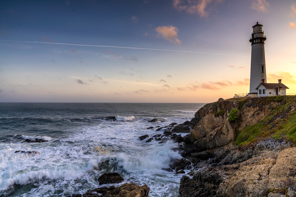 a lighthouse sitting on top of a cliff next to the ocean