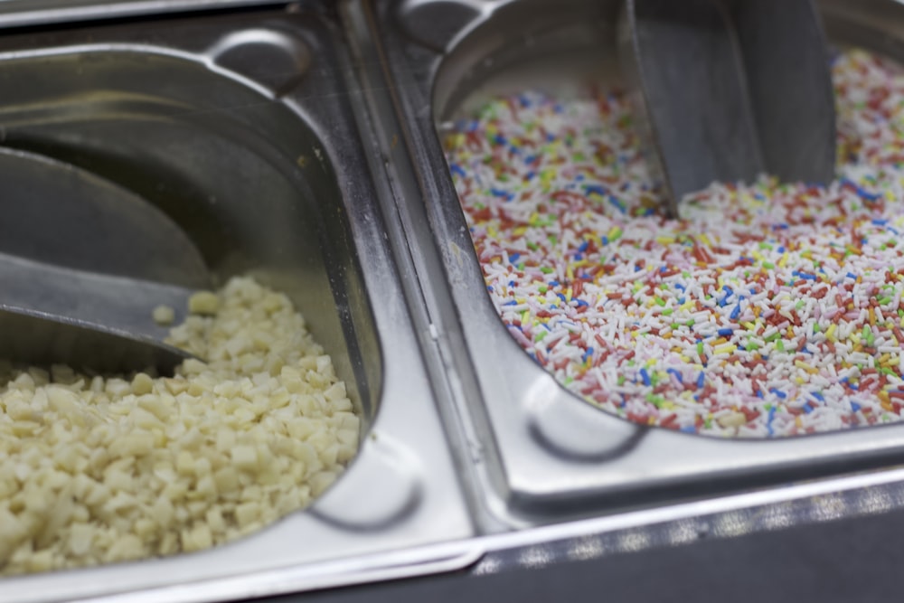 a couple of trays filled with rice and sprinkles