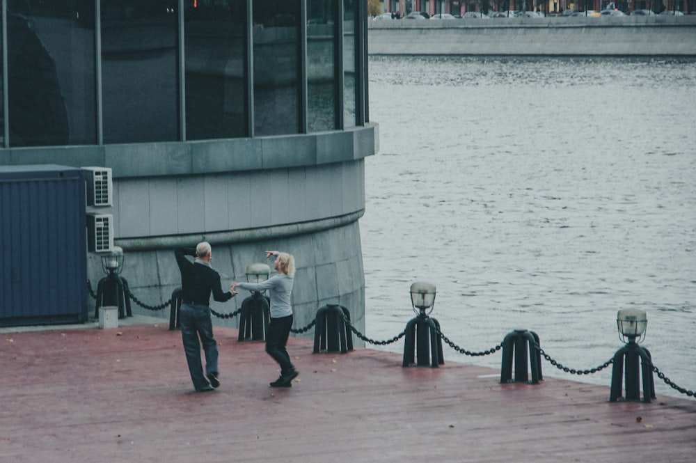 a couple of men standing next to each other near a body of water