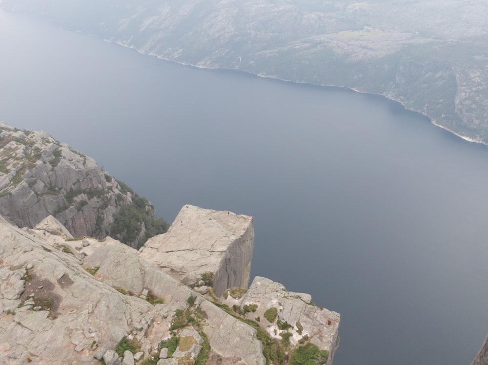 a man standing on top of a cliff next to a body of water