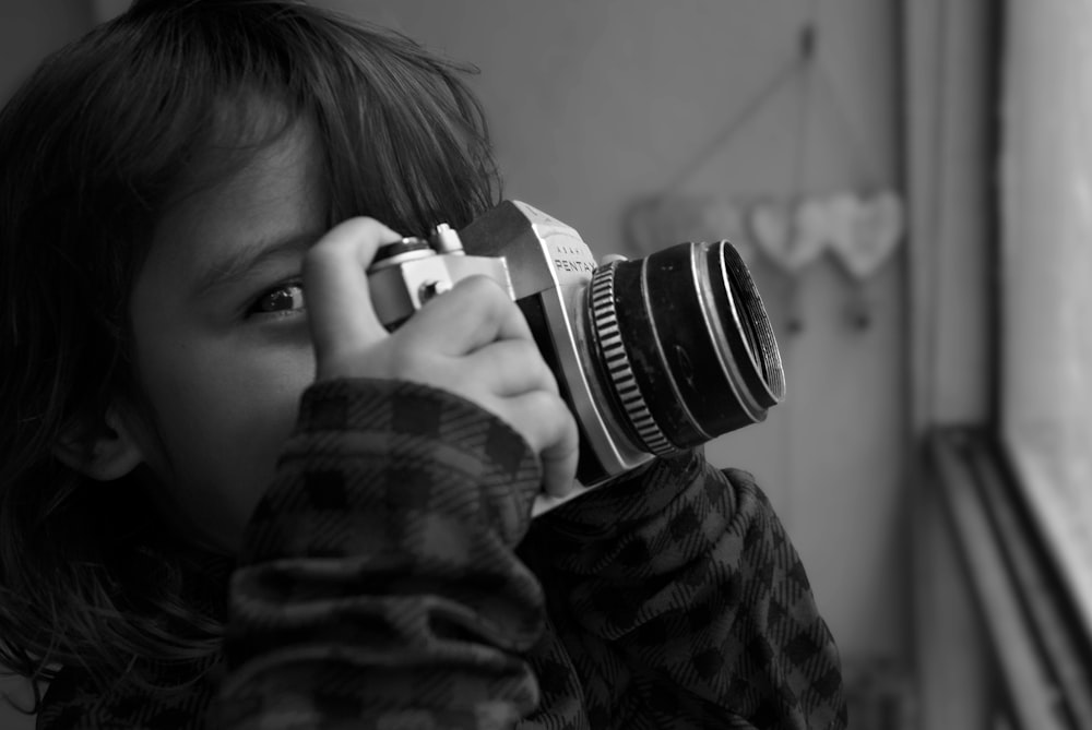 a little girl holding a camera up to her face