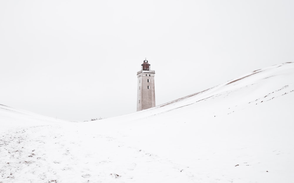 uma torre alta sentada no topo de uma colina coberta de neve