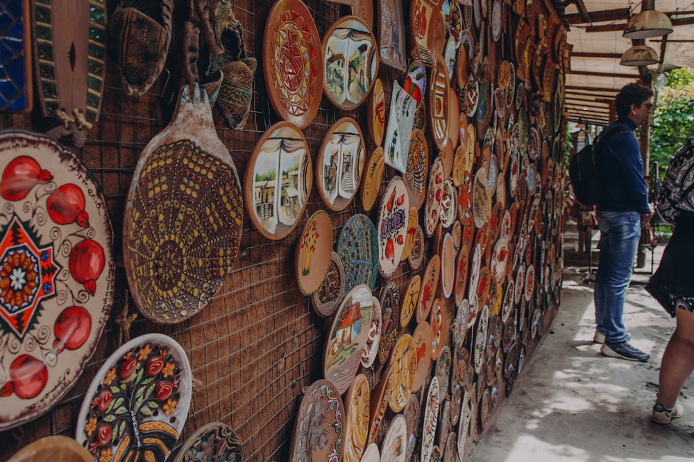 a woman standing next to a wall covered in plates