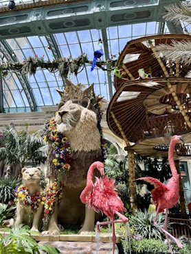 a statue of a lion and two flamingos in a garden