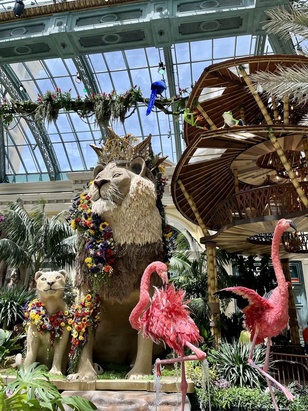 a statue of a lion and two flamingos in a garden