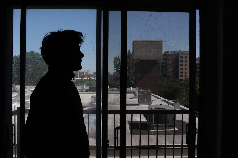 a silhouette of a man standing in front of a window