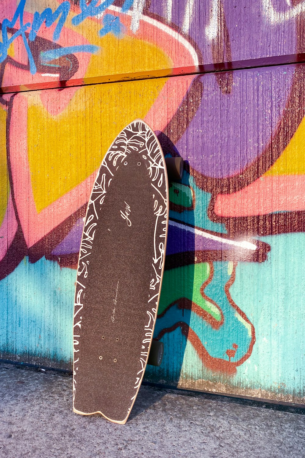 Un skateboard appuyé contre un mur couvert de graffitis