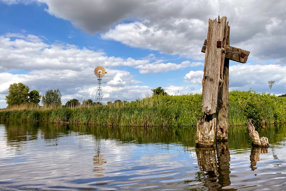 a wooden cross sitting in the middle of a lake