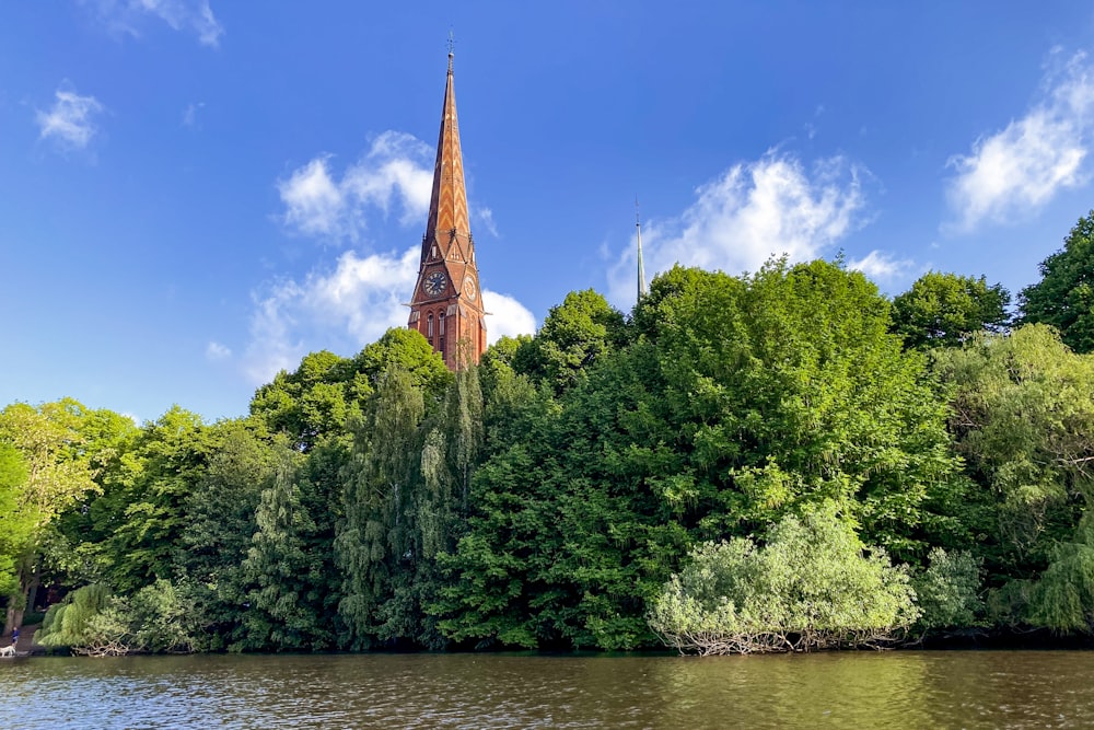 a church steeple towering over a river surrounded by trees