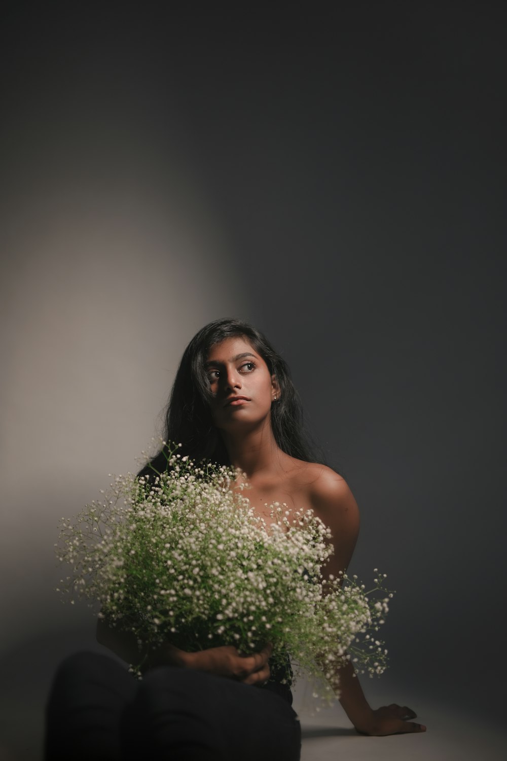 a woman sitting on the ground holding a bouquet of flowers