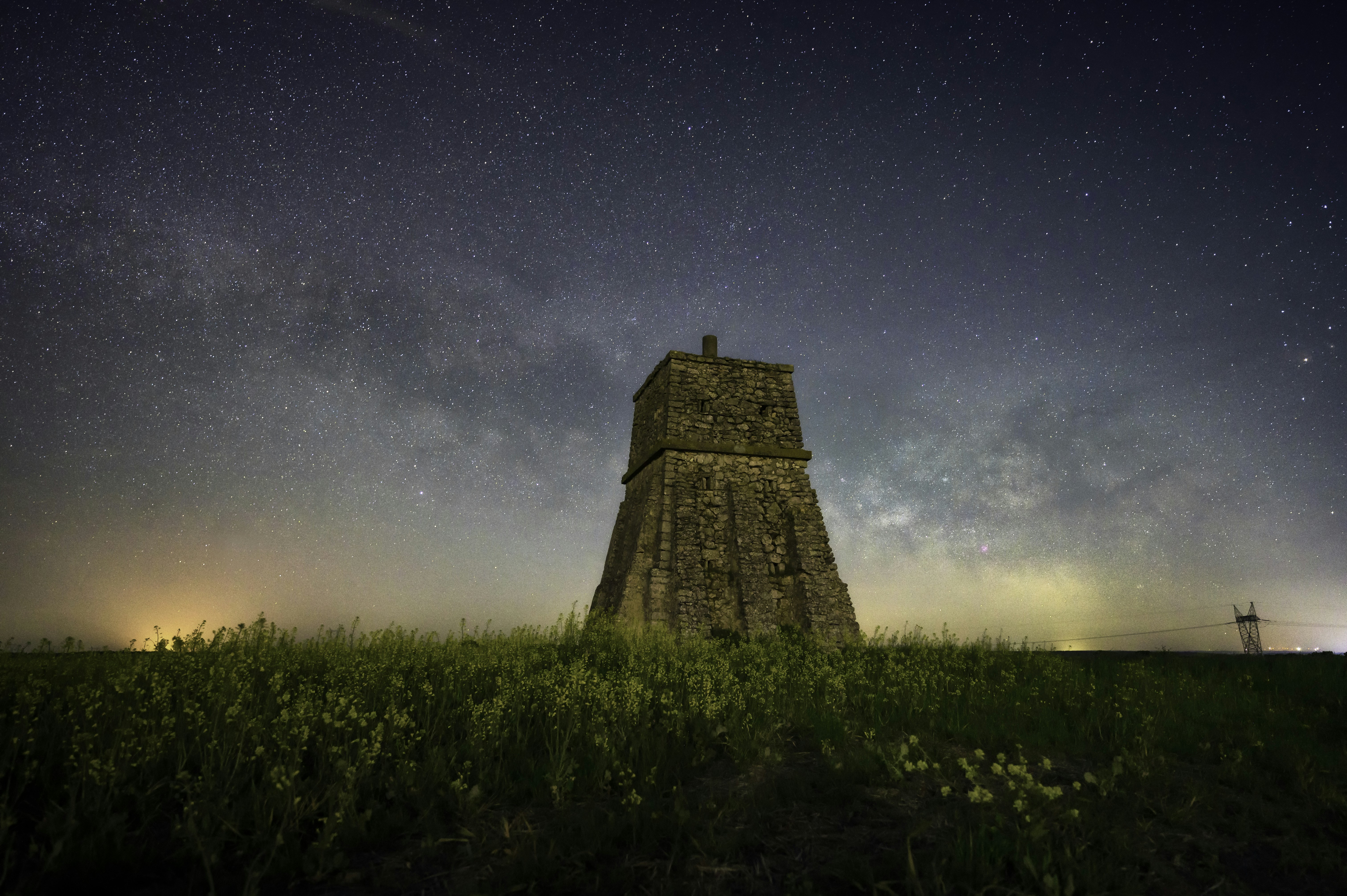 Ancient stone observatory tower at night with a star-filled sky, warm amber torchlight illuminating carved stone walls