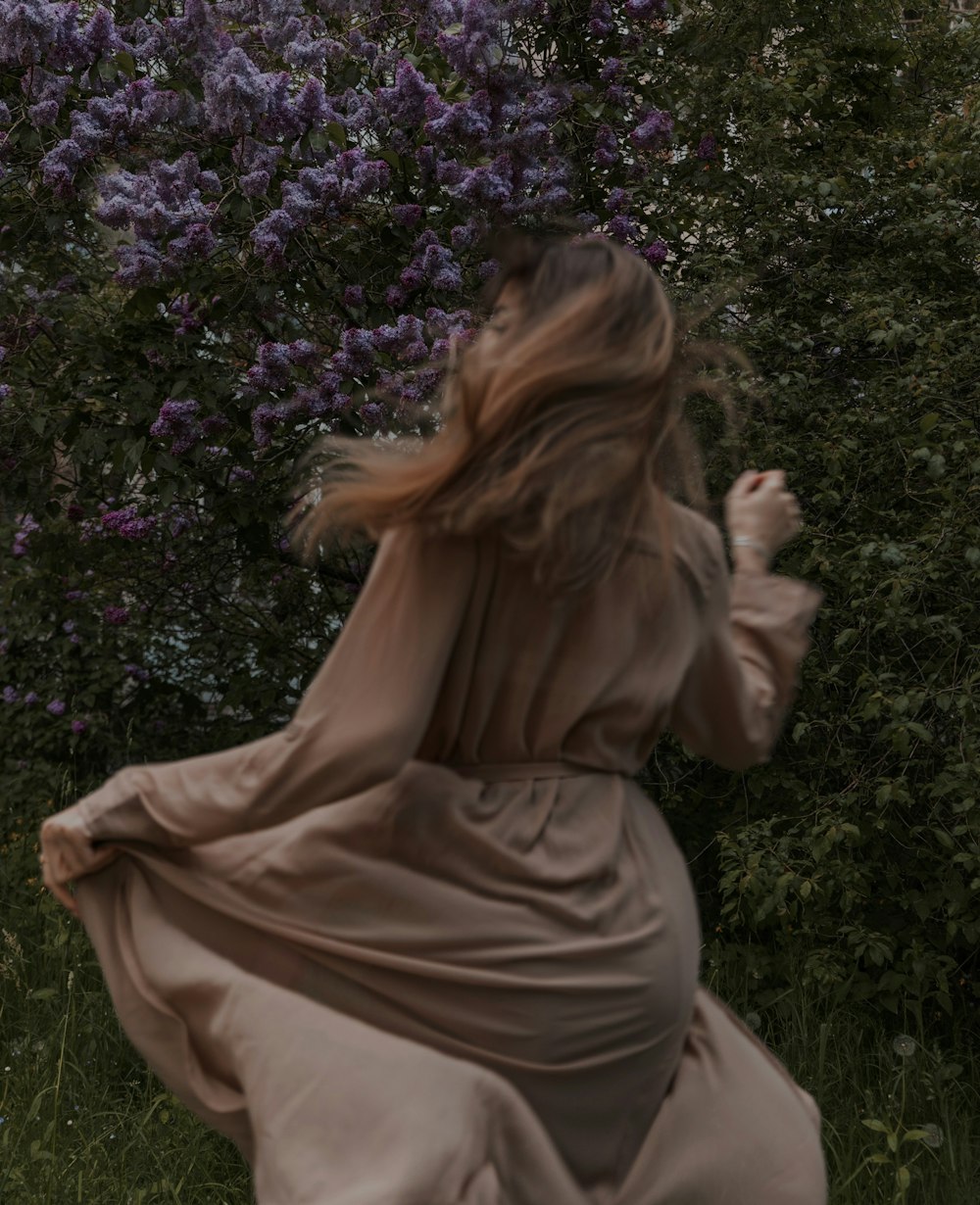 a woman in a long dress walking through a field
