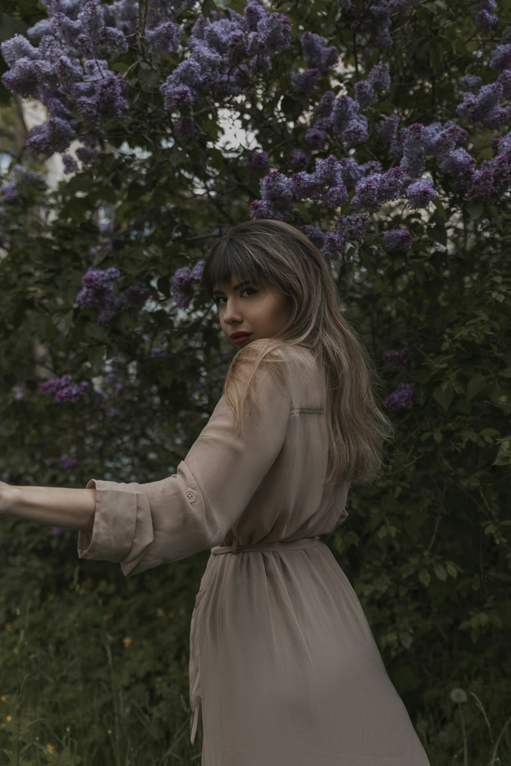 a woman standing in front of a tree with purple flowers