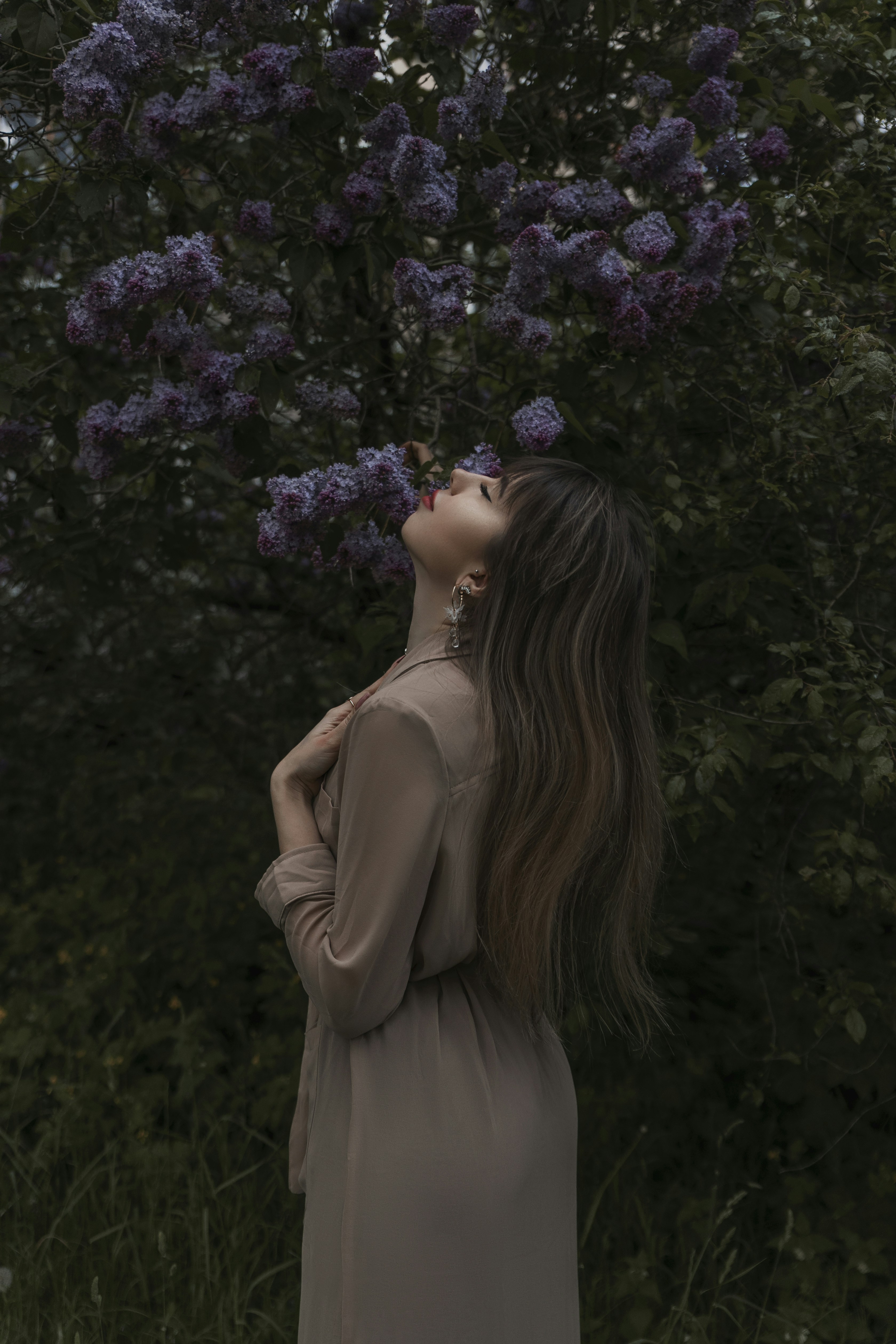 a woman standing in front of a tree with purple flowers