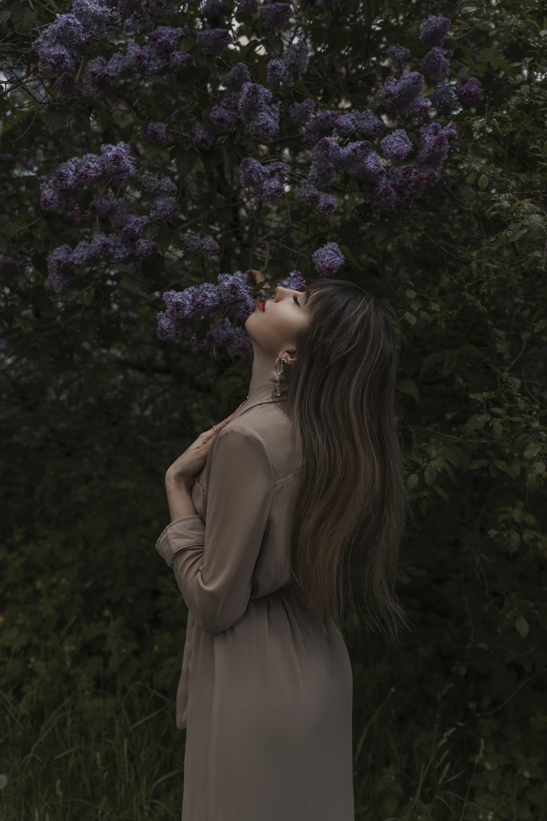 a woman standing in front of a tree with purple flowers