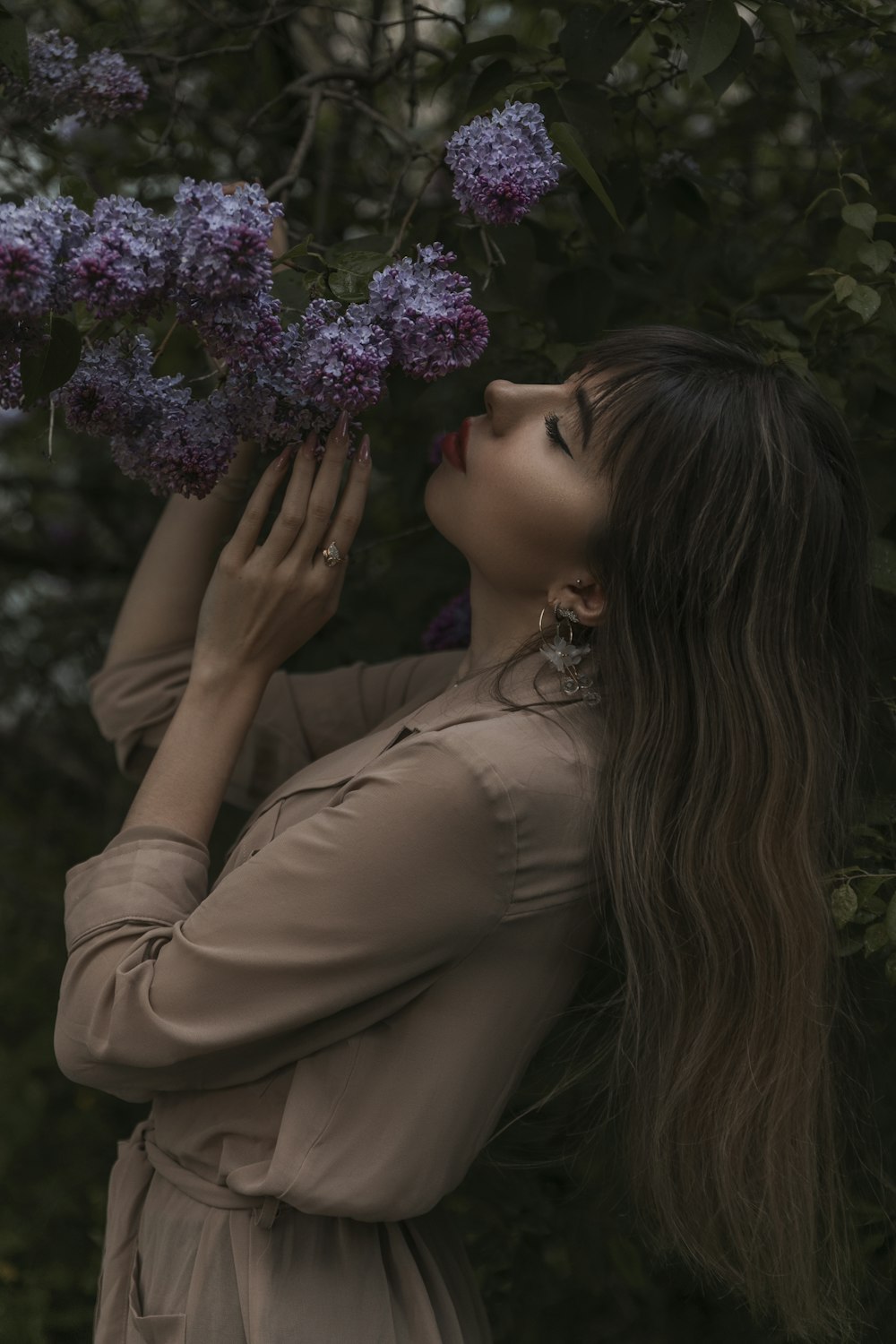 a woman in a brown dress holding a bunch of purple flowers