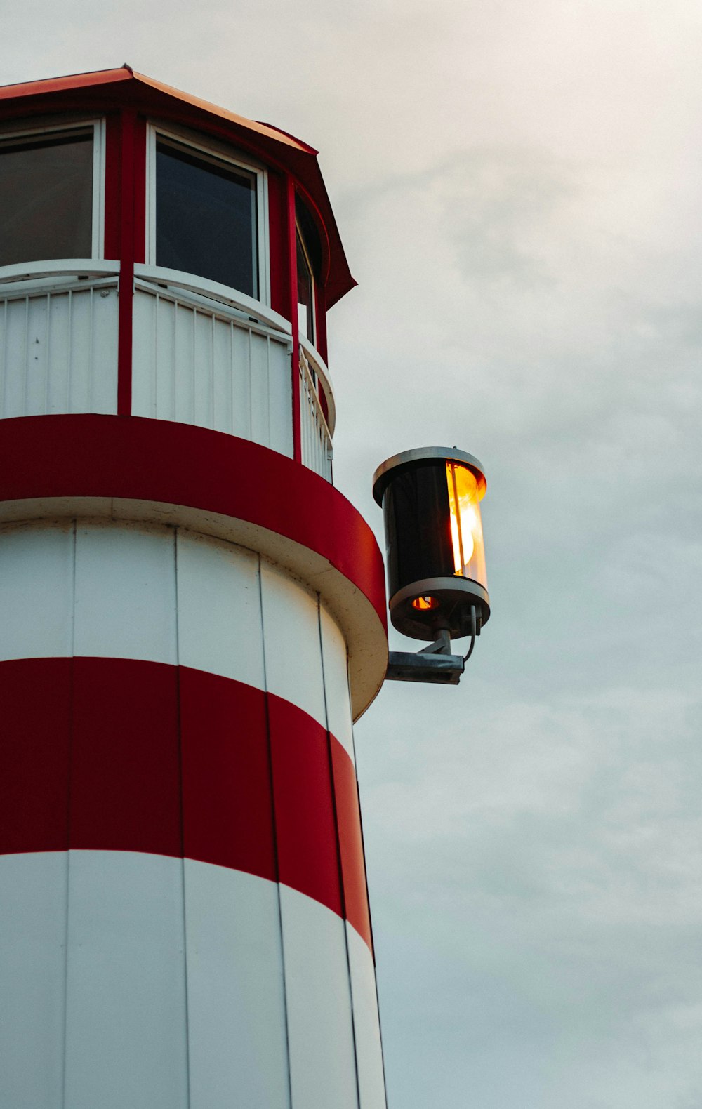 a red and white light house on a cloudy day