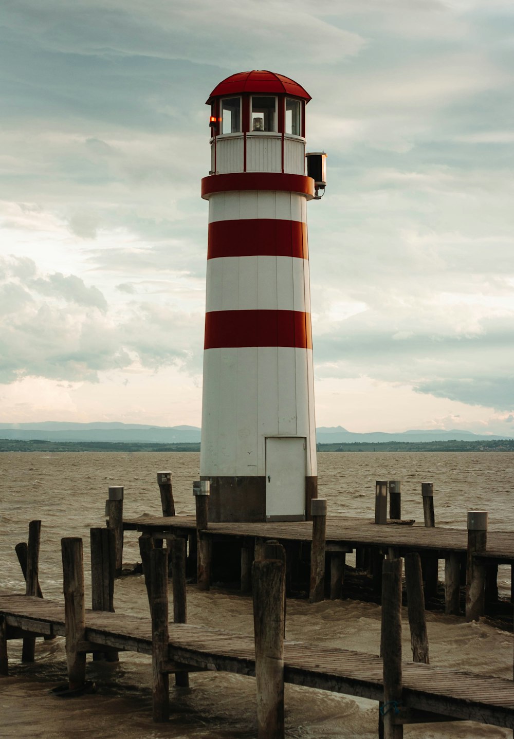 a red and white lighthouse sitting on top of a pier