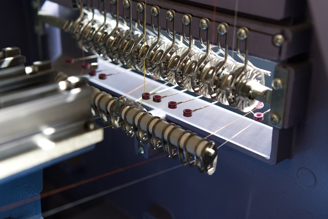 a close up of a machine that is working, Close-up of an industrial knitting machine used for textile manufacture.