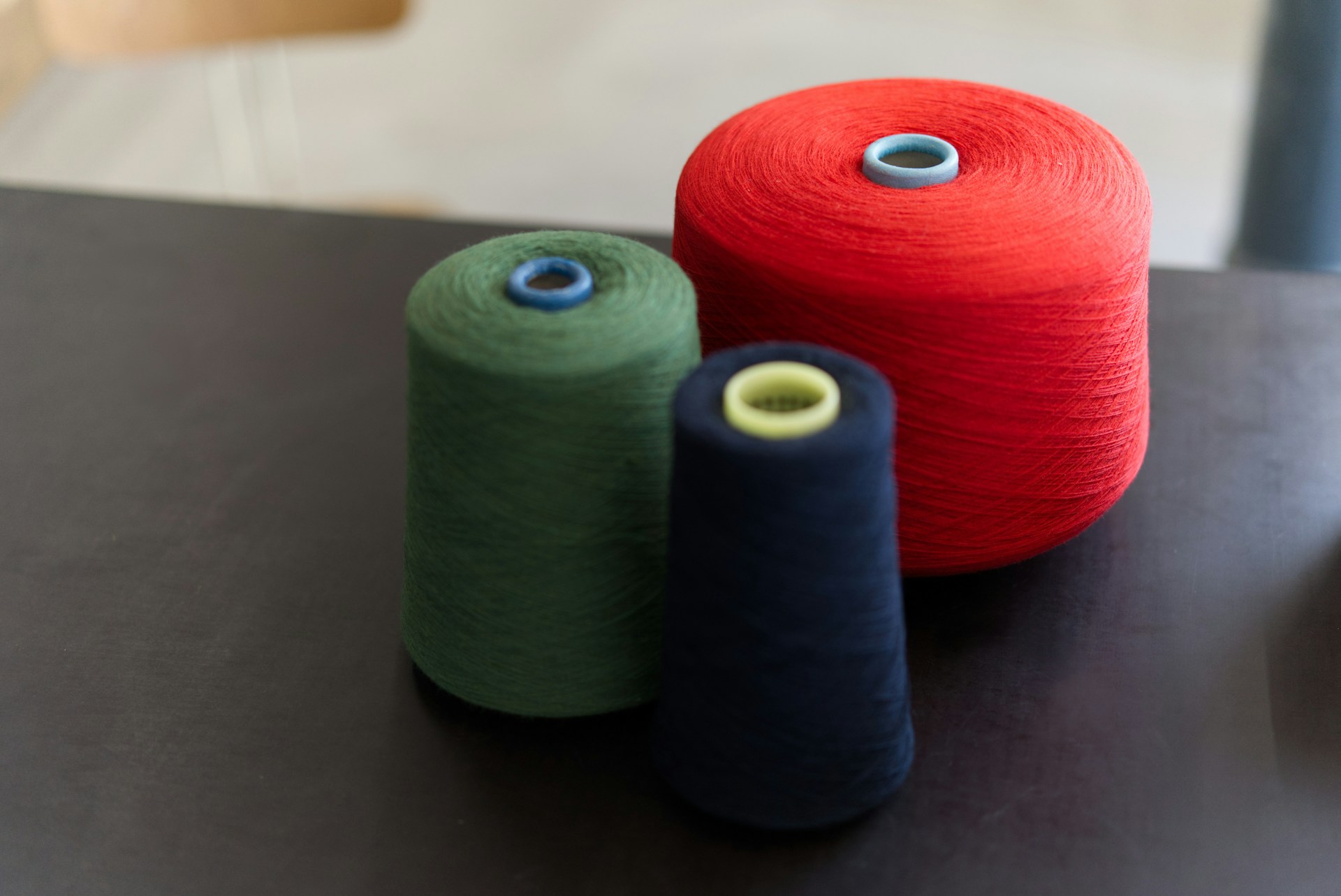 three different colored spools of yarn on a table