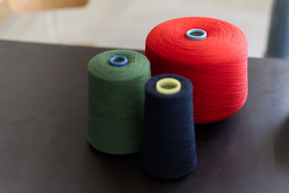 three different colored spools of yarn on a table