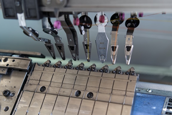 A close-up of a mechanical assembly featuring several metal components and tools, possibly part of a larger industrial or manufacturing machine. Various levers, grips, and fixtures are visible, suggesting a precise and technical function.