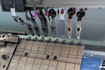 A close-up of a mechanical assembly featuring several metal components and tools, possibly part of a larger industrial or manufacturing machine. Various levers, grips, and fixtures are visible, suggesting a precise and technical function.