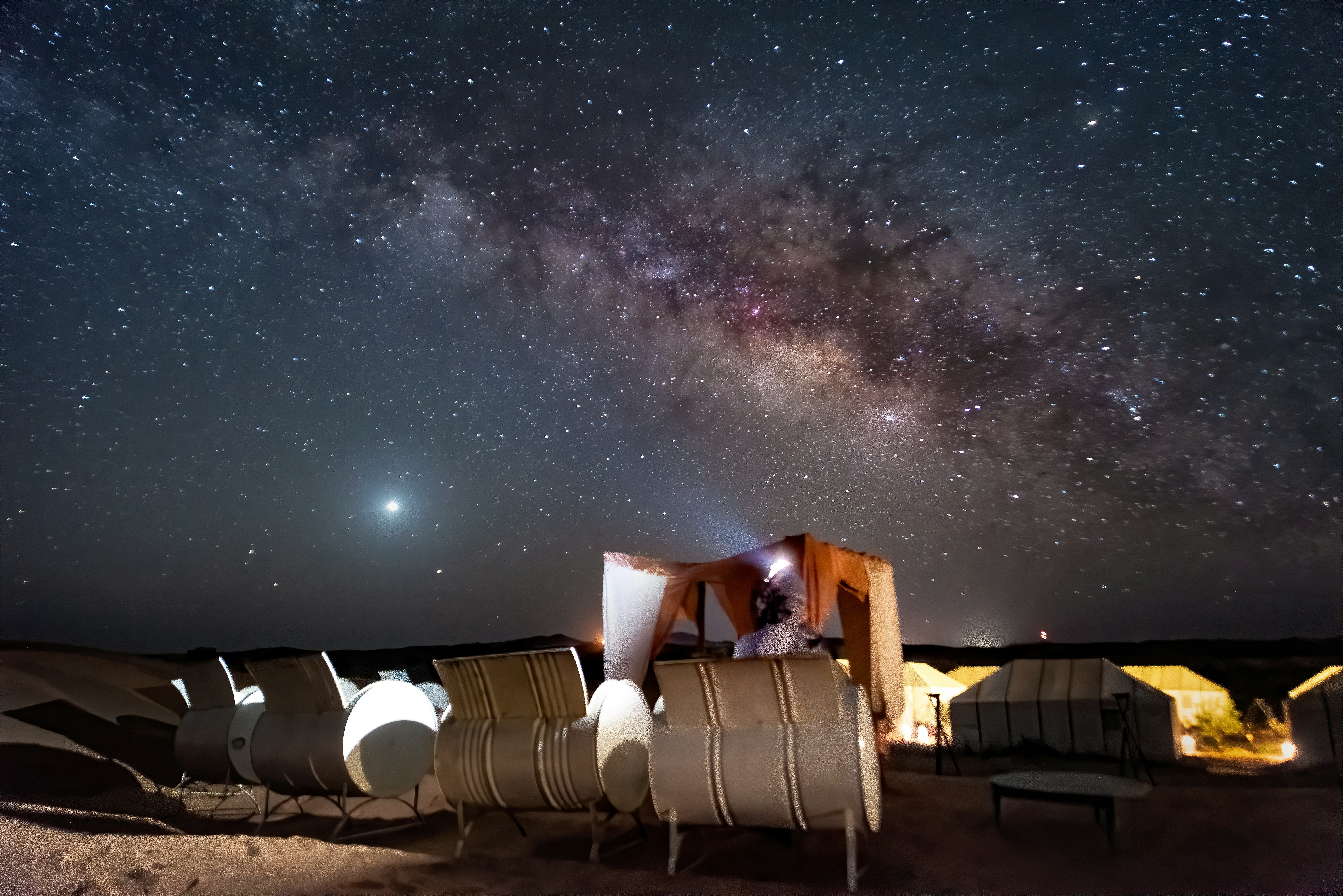 Moroccan desert camp at night with stars and traditional Berber tents under the Milky Way