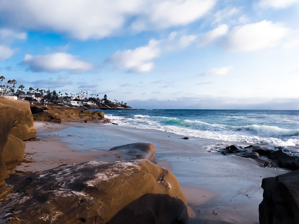 a sandy beach next to the ocean under a cloudy sky