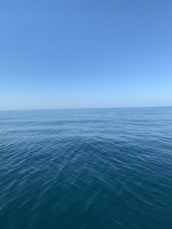 A panoramic view of a calm sea stretching to the horizon under a clear blue sky.