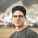 a young man wearing glasses standing in front of a mountain
