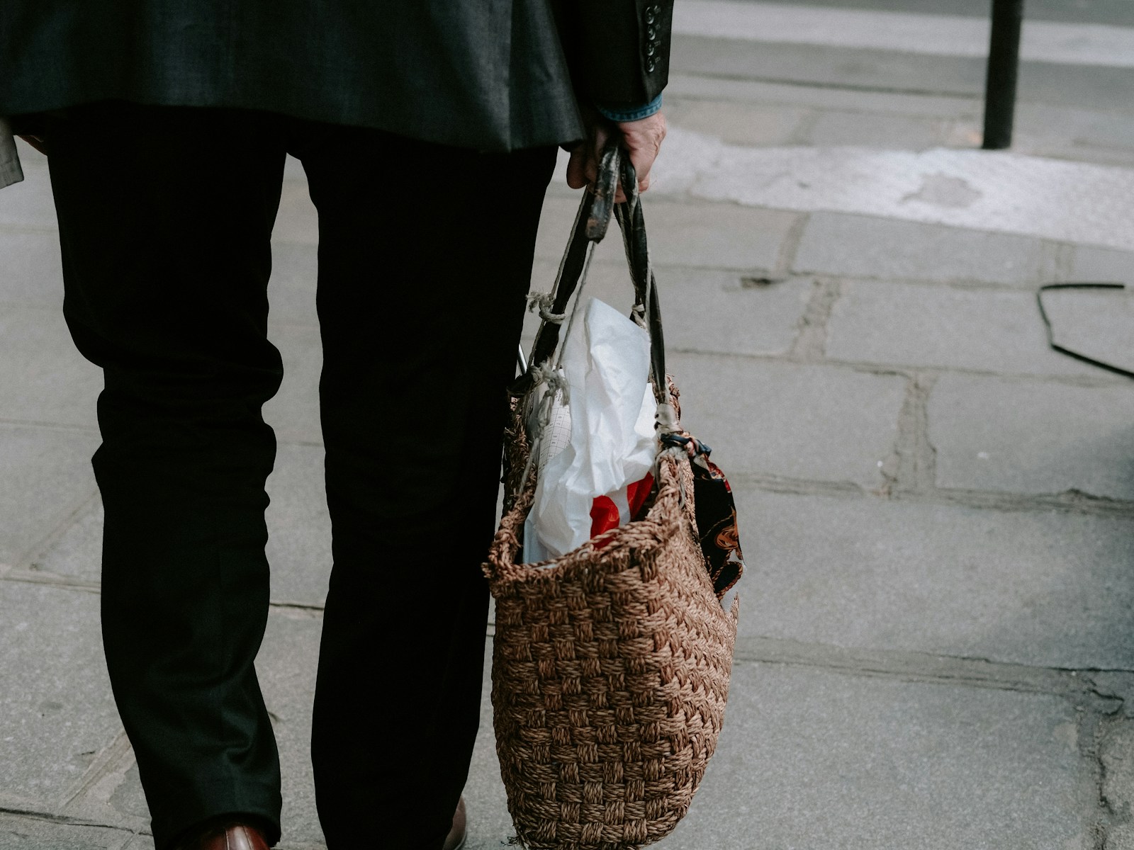 a person walking down a sidewalk carrying a basket