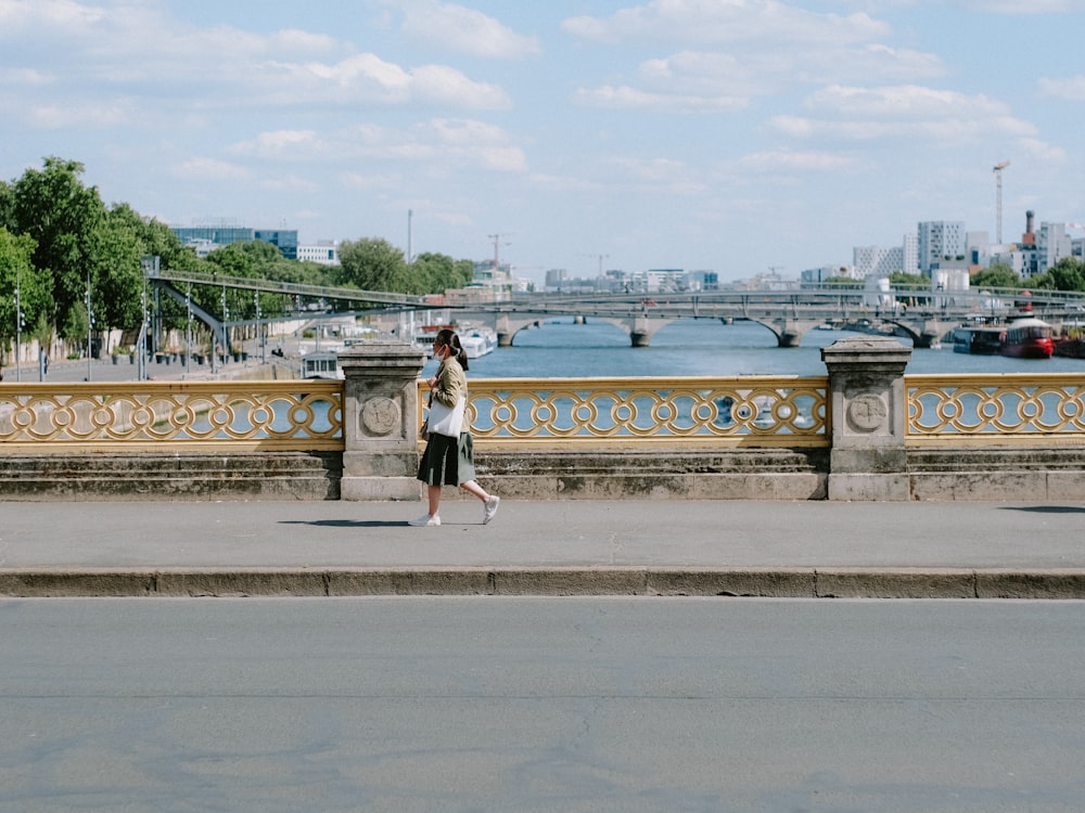 a man walking across a bridge with a skateboard